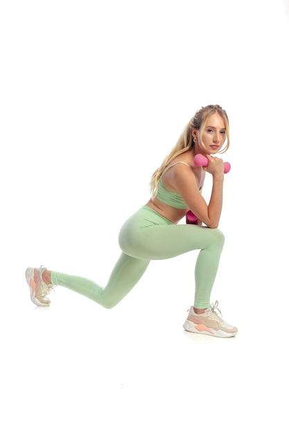 Mujer en forma entrenando con mancuernas en leggins foto gratis