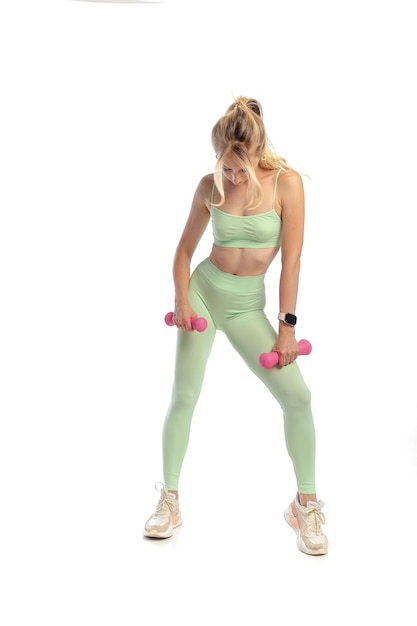 Mujer en forma entrenando con mancuernas en leggins foto gratis