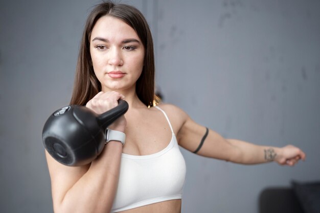 Mujer en forma entrenando con tiro medio de pesas rusas