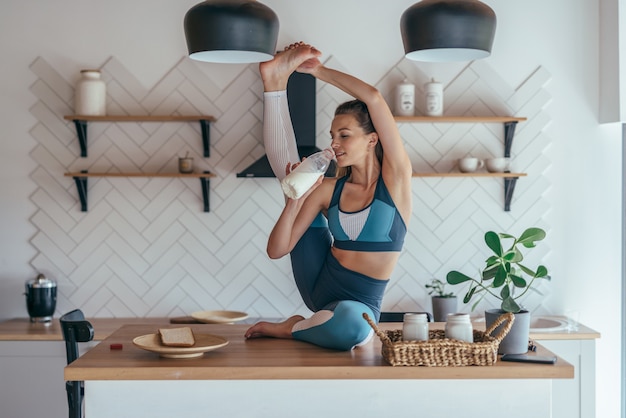 La mujer en forma está calentando y comiendo al mismo tiempo.