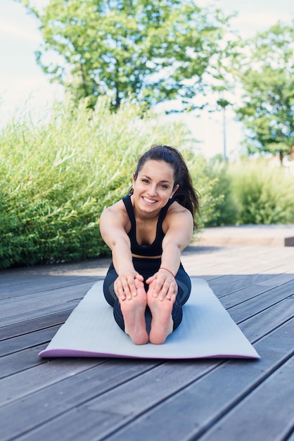 Una mujer en forma estirando la parte superior del cuerpo antes de entrenar en las calles de la ciudad en una mañana soleada de verano selectiva