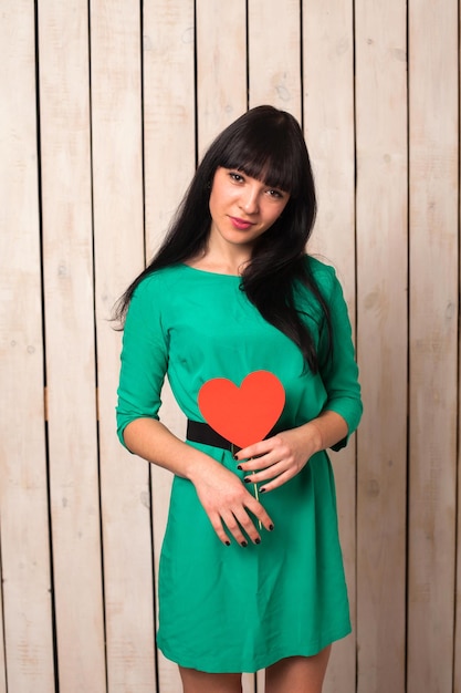 Mujer con forma roja de corazón en vestido verde en el día de San Valentín