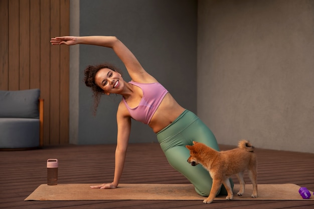 Foto mujer en forma de tiro completo haciendo deporte con perro en el interior