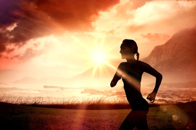 Mujer en forma trotando contra el amanecer sobre el mar mágico