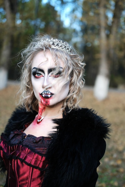 Una mujer en forma de vampiro o bruja con maquillaje blanco en la cara.