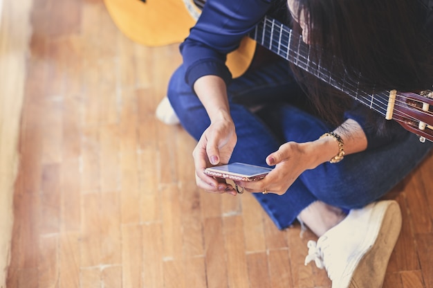 Mujer formación guitarra con el uso de teléfonos inteligentes móviles.