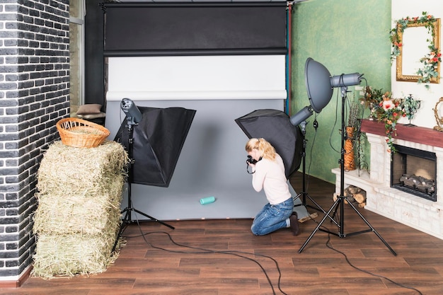 Foto mujer fotógrafa en estudio fotografiando objetos sobre fondo gris, primer plano