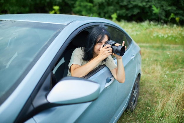 Mujer fotógrafa sentada en el camión y fotografiando un paisaje de campo de flores, mujer de viaje toma una foto, espacio para texto.