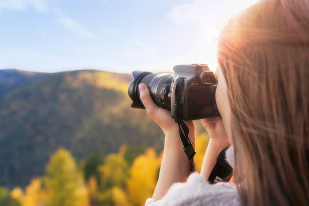 Una mujer fotógrafa toma fotografías de la naturaleza con una vista de primer plano de la cámara desde el espacio libre posterior Viajes de otoño y estilo de vida activo
