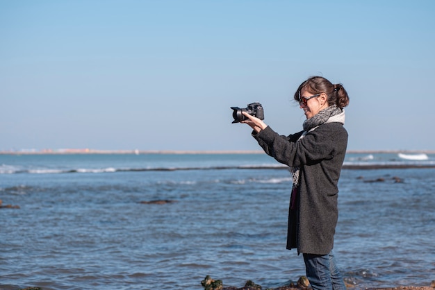 mujer fotógrafa tomando fotos en la costa