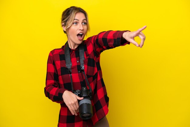 Mujer fotógrafa uruguaya aislada de fondo amarillo apuntando hacia otro lado