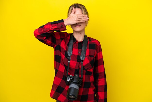 Mujer fotógrafa uruguaya aislada de fondo amarillo cubriendo los ojos con las manos No quiero ver algo