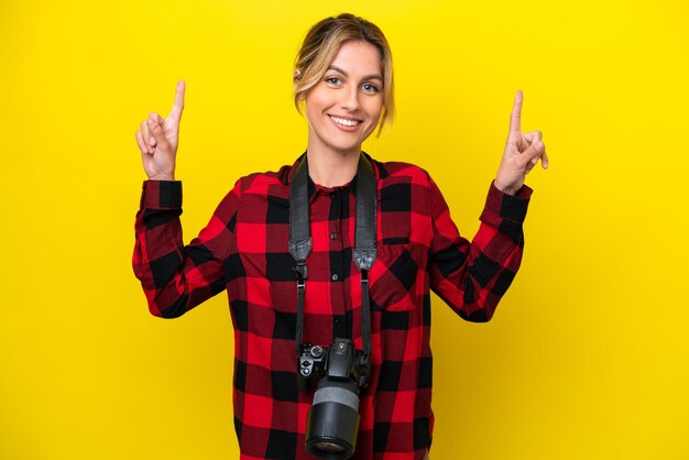 Mujer fotógrafa uruguaya aislada de fondo amarillo señalando una gran idea