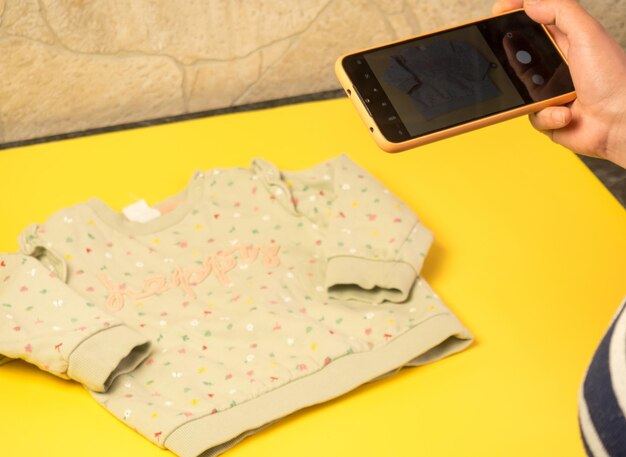 Una mujer fotografía ropa infantil a la online el concepto de vender ropa online ropa de segunda mano | Foto Premium