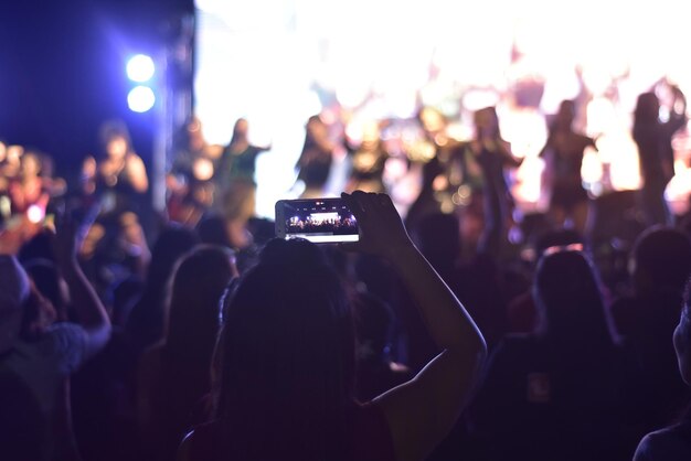 Foto mujer fotografiando en un concierto de música