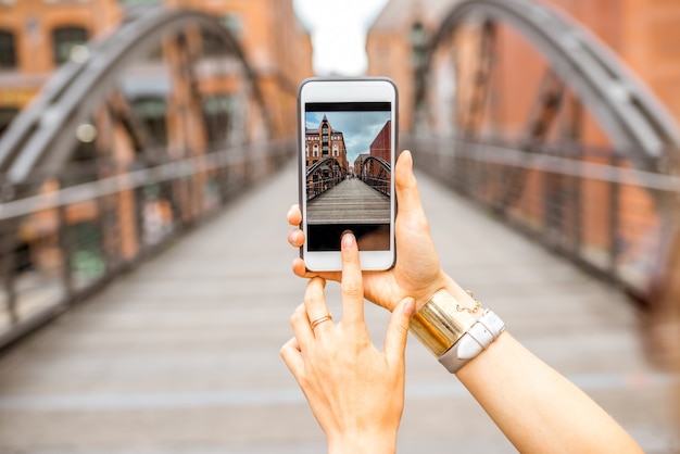 Mujer fotografiando con smartphone viejo puente de hierro en Hamburgo, Alemania.