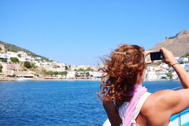 Mujer fotografiando a través de un teléfono móvil contra el cielo