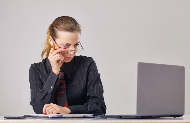 Mujer frente a la computadora mirando por encima de sus lentes