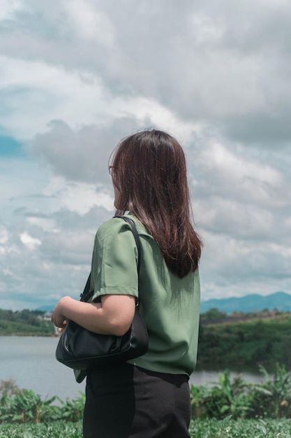 Una mujer se para frente a un lago y mira al cielo.