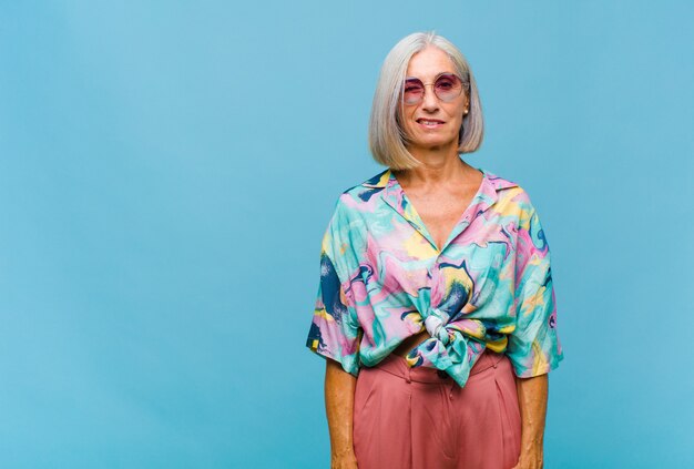 Mujer fresca de mediana edad que se ve feliz y amigable, sonriendo y guiñando un ojo con una actitud positiva