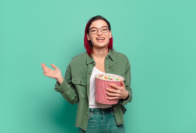 Mujer fresca de pelo rojo con palomitas de maíz y un control remoto de tv