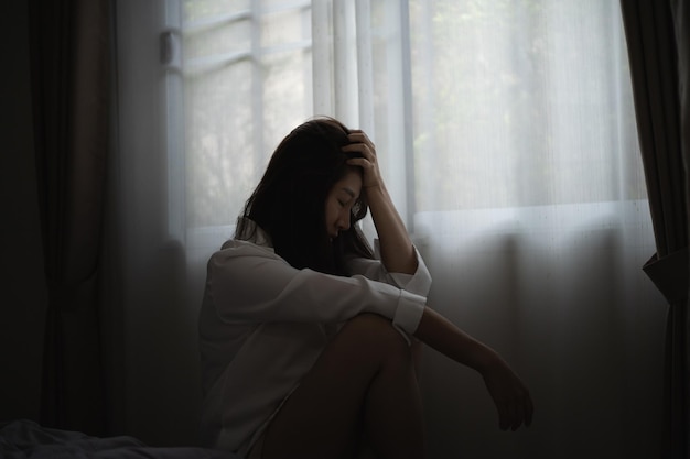 Mujer frustrada sentada junto a la ventana en casa