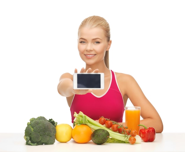 mujer con frutas y verduras contando calorías en el teléfono inteligente