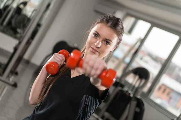 Mujer fuerte levantamiento de pesas en el gimnasio mirando feliz