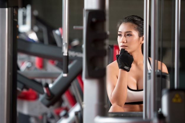 mujer fuerte relajante en el gimnasio. Fitness femenino tomando un descanso de entrenamiento intenso.