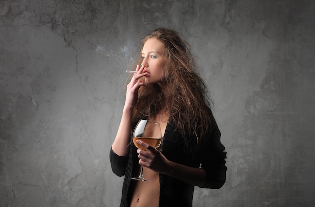 Mujer fumando bebiendo vino