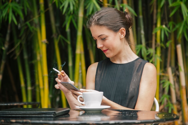 Mujer fumando usando internet en su teléfono