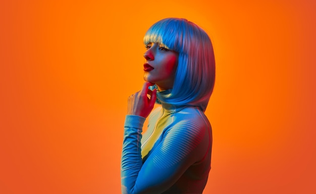 Mujer futurista con peluca azul contra la luz naranja