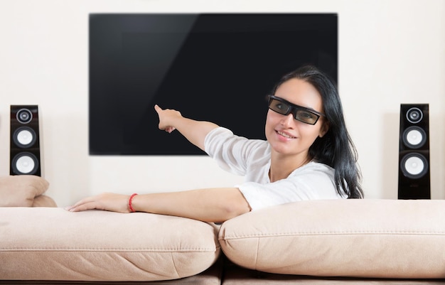 Mujer con gafas 3d apuntando al sistema de cine en casa