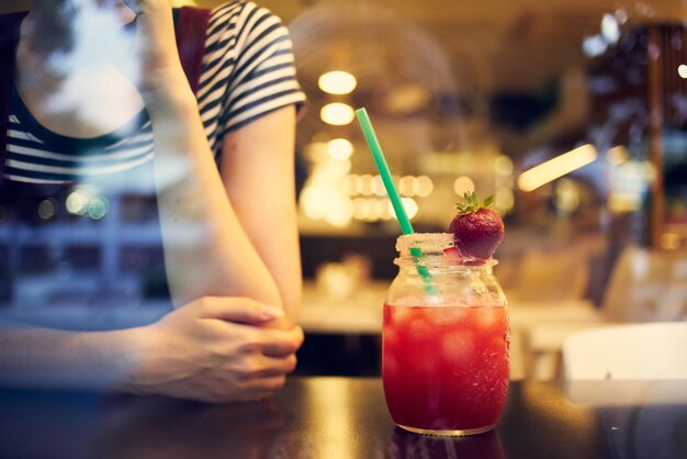 Una mujer con gafas con un peinado corto se sienta sola en un cóctel de restaurante