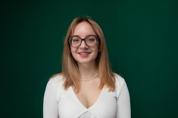 Mujer con gafas de pie frente al fondo verde