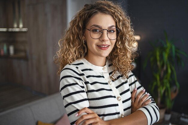 Mujer con gafas de pie frente a un sofá