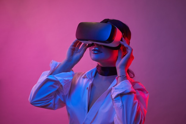 Mujer con gafas de realidad virtual en las luces de neón. Chica en gafas de realidad virtual con experiencia.