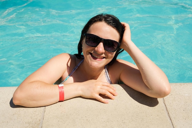 Una mujer con gafas de sol descansa en la piscina.