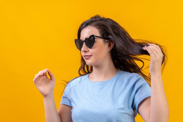 Mujer con gafas de sol en forma de corazón arreglando su cabello