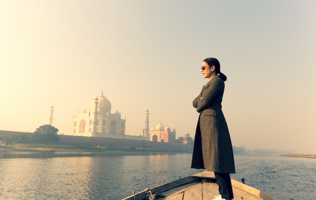 Mujer con las gafas de sol que llevan que se colocan en un barco con Taj Mahal en fondo.