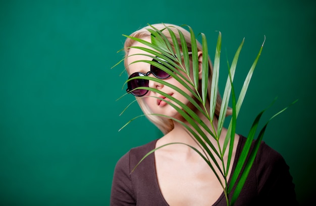 Mujer en gafas de sol con rama de palma en escena verde