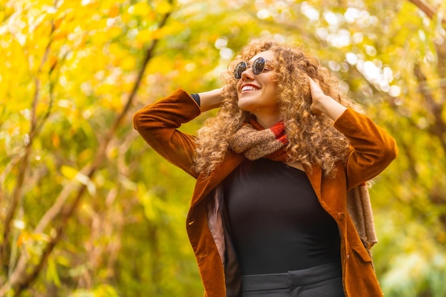 Foto mujer con gafas de sol y ropa casual mirando en un parque durante el otoño