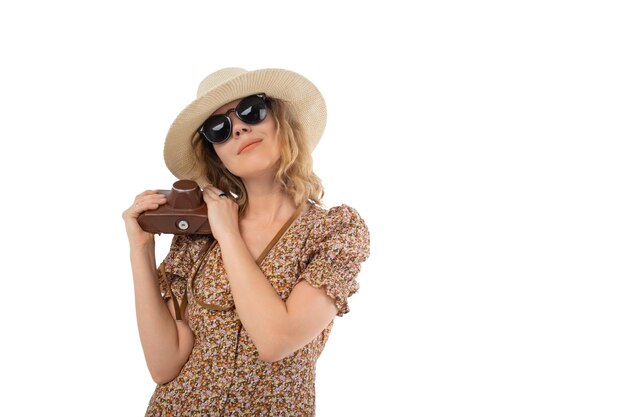 Mujer con gafas de sol vestido marrón con sombrero con cámara retro aislada en fondo blanco