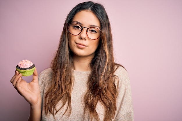 Una mujer con gafas sosteniendo una magdalena verde.