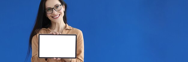 Foto mujer con gafas sosteniendo tableta digital con pantalla blanca en sus manos