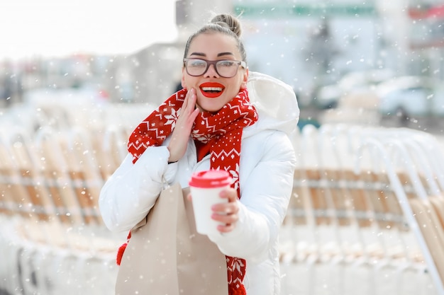 Mujer con gafas y suéter rojo de cerca en la calle tomando café