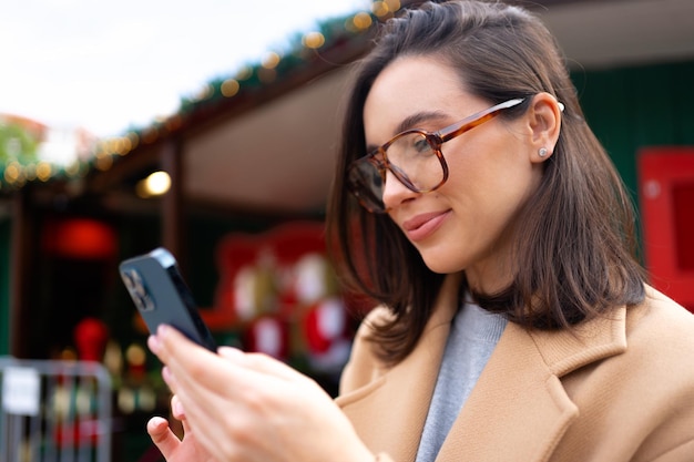 Foto mujer con gafas usando teléfono móvil durante el día en la ciudad