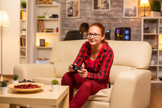 Mujer gamer jugando videojuegos en la consola en la sala de estar a altas horas de la noche