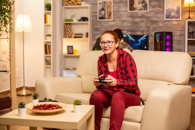 Mujer gamer jugando videojuegos en la consola en la sala de estar a altas horas de la noche