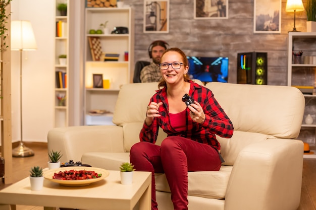 Mujer gamer jugando videojuegos en la consola en la sala de estar a altas horas de la noche